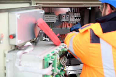Professional engineer inspecting industrial electrical circuit board, ensuring safety standards. 